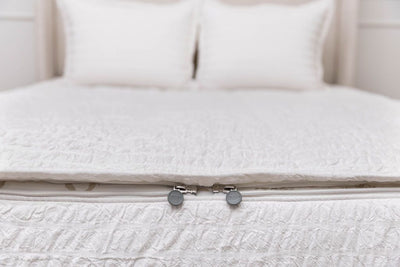The foot of a bed made with seersucker white zipper bedding showing where the two zippers are located.