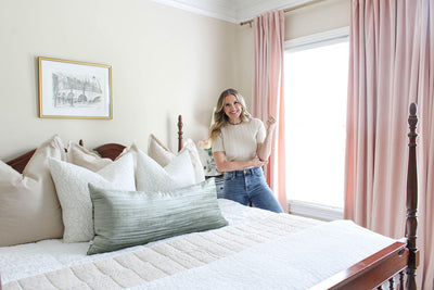 Interior designer Mallory Nikolaus standing beside a bed made with the zipper bedding set she designed.
