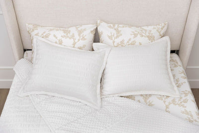 A bed made with seersucker white zipper bedding with the comforter pulled back and pillows on top of the bed.