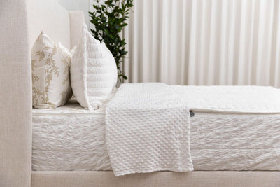 A side view of a bed made with seersucker white zipper bedding with the top unzipped halfway down the bed and the comforter folded down.