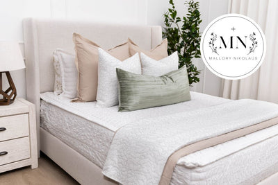 A queen bed made with white seersucker zipper bedding and an assortment of neutral bedding accessories, designed by interior designer Mallory Nkolaus