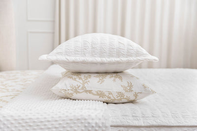 A white seersucker sham stacked on top of a neutral floral pillowcase, on top of a bed made with white seersucker zipper bedding.