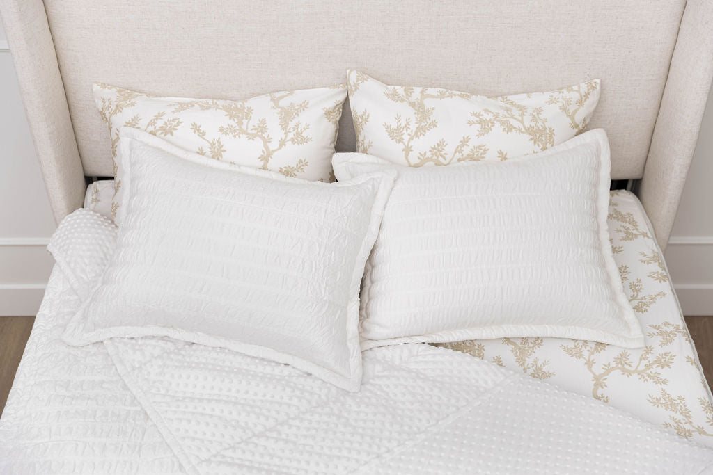 Aerial view of a bed made with white seersucker zipper bedding, the top pulled back to reveal the minky lining, two pillowcases and two shams on top of the bed