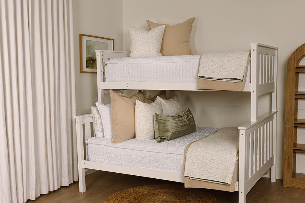 A bunk bed made with seersucker white zipper bedding and an assortment of neutral throw pillows and blankets.