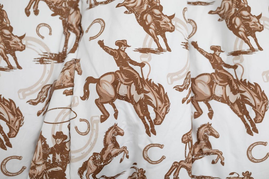A close up of a cowboy on a horse with horseshoes in the background printed brown and white pattern blanket.