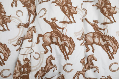 A close up of a cowboy on a horse with horseshoes in the background printed brown and white pattern blanket.
