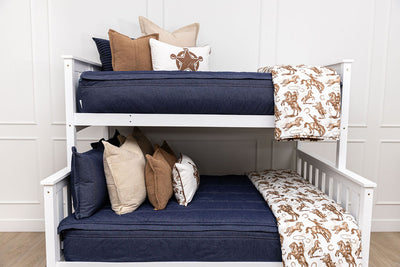 A standard bunk bed with both bunks made with dark denim blue zipper bedding and neutral pillows and a cowboy western printed blankets.