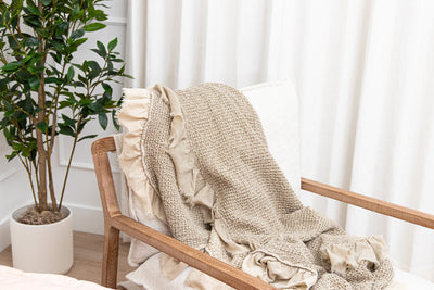 A tan waffle textured throw blanket folded over a chair.