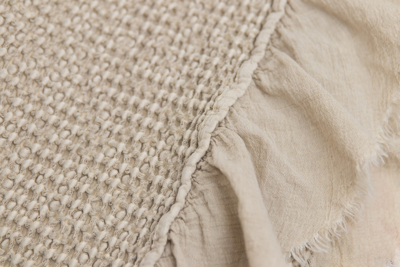 A close up view of the details of a tan waffle textured throw blanket.