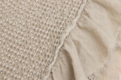 A close up view of the details of a tan waffle textured throw blanket.