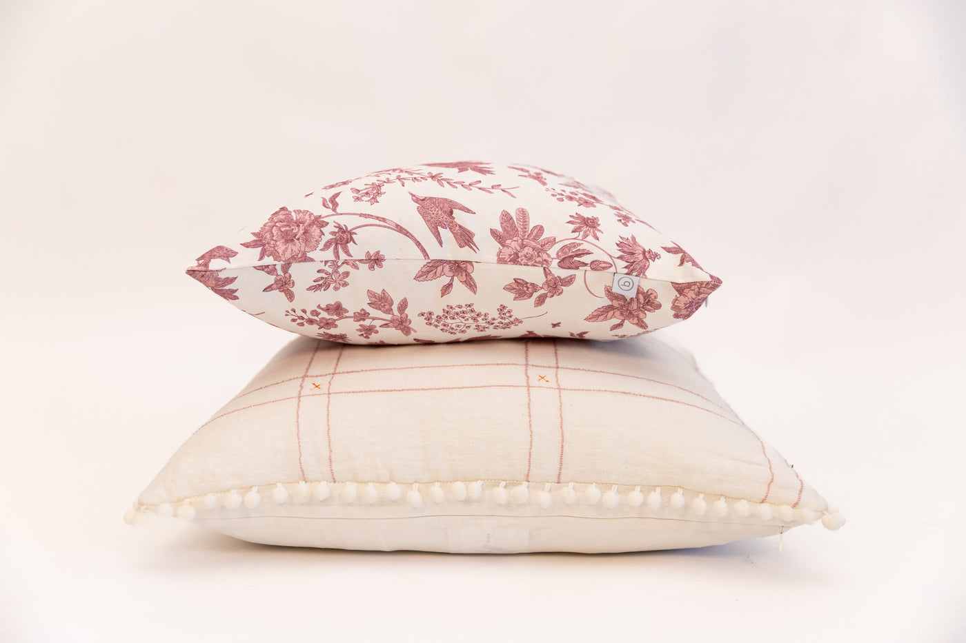 White pillow and pink pillow stacked on white background