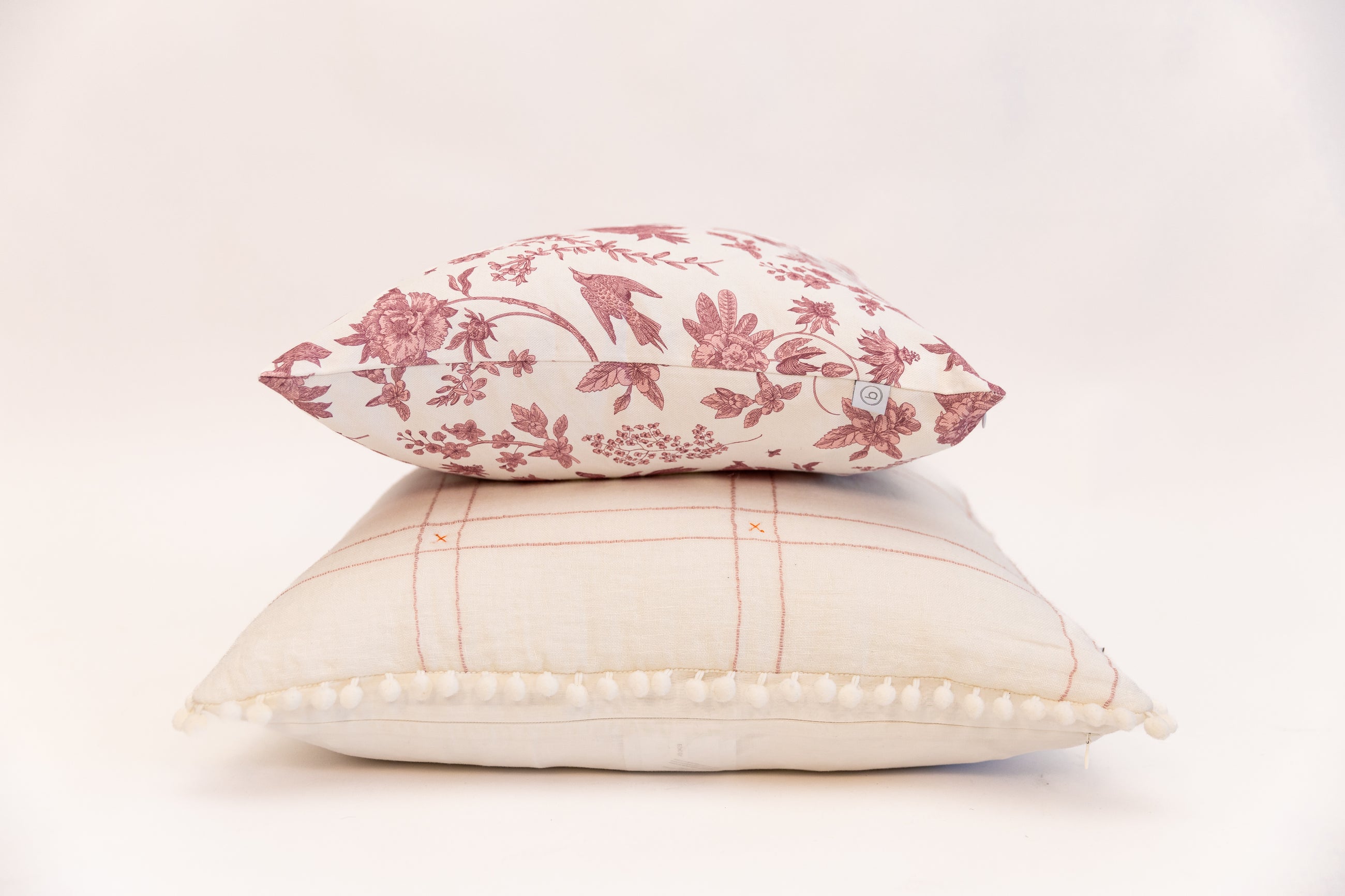 White pillow and pink pillow stacked on white background