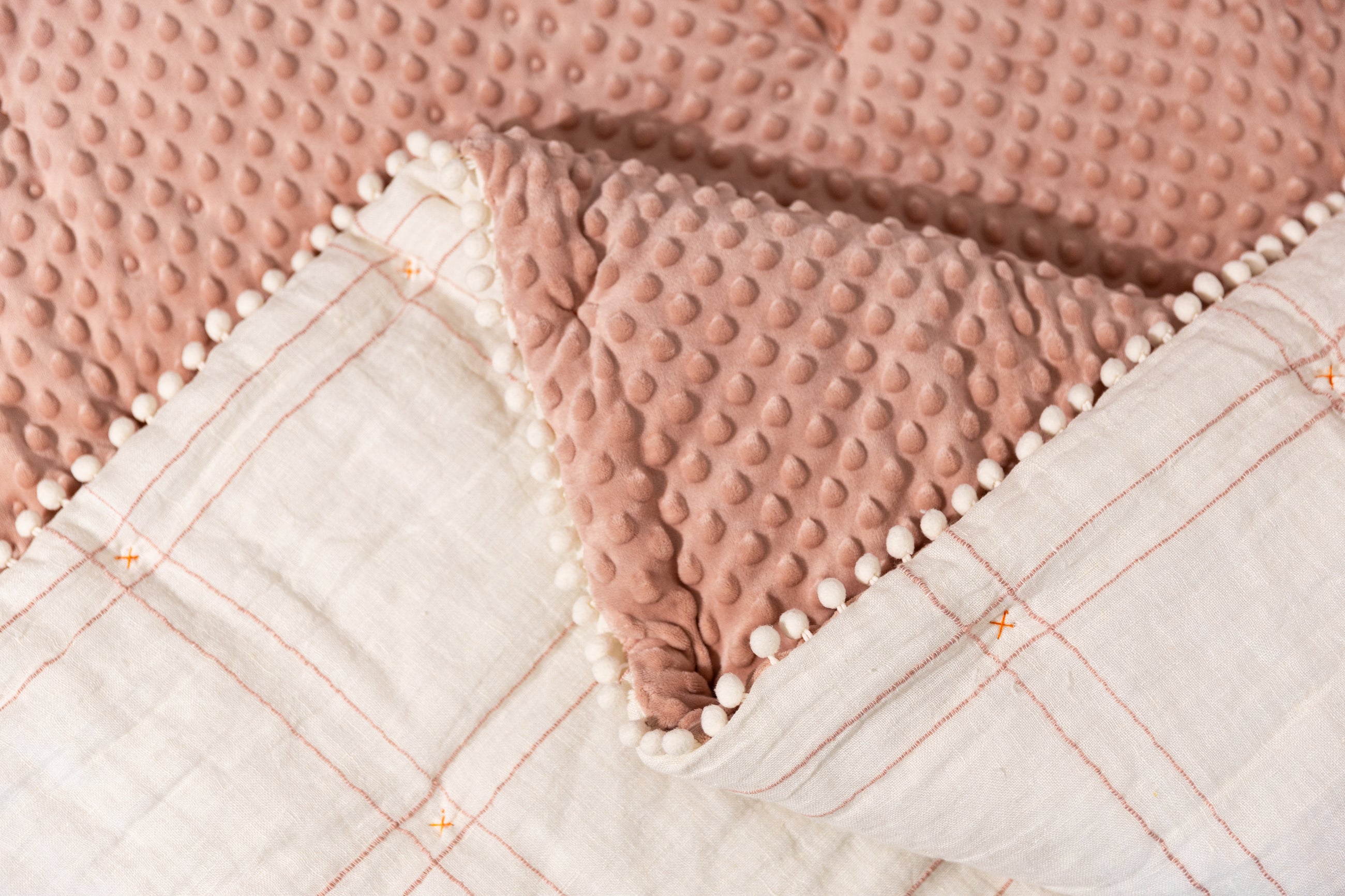 Photo with both pink minky and white grid side of blanket