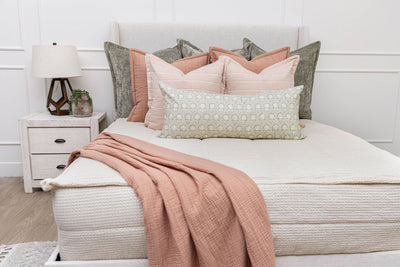 A cream waffle knit zipper bedding set decorated with pink and green throw pillows and a pink blanket