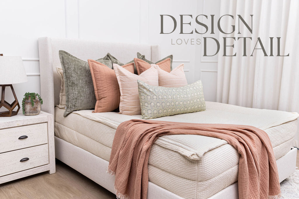 A queen bed made with cream waffle zipper bedding and an assortment of pink and green pillows, all designed by Design Loves Detail
