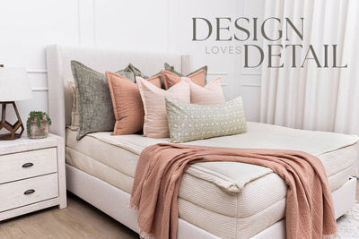 A queen bed made with cream waffle zipper bedding and an assortment of pink and green pillows, all designed by Design Loves Detail