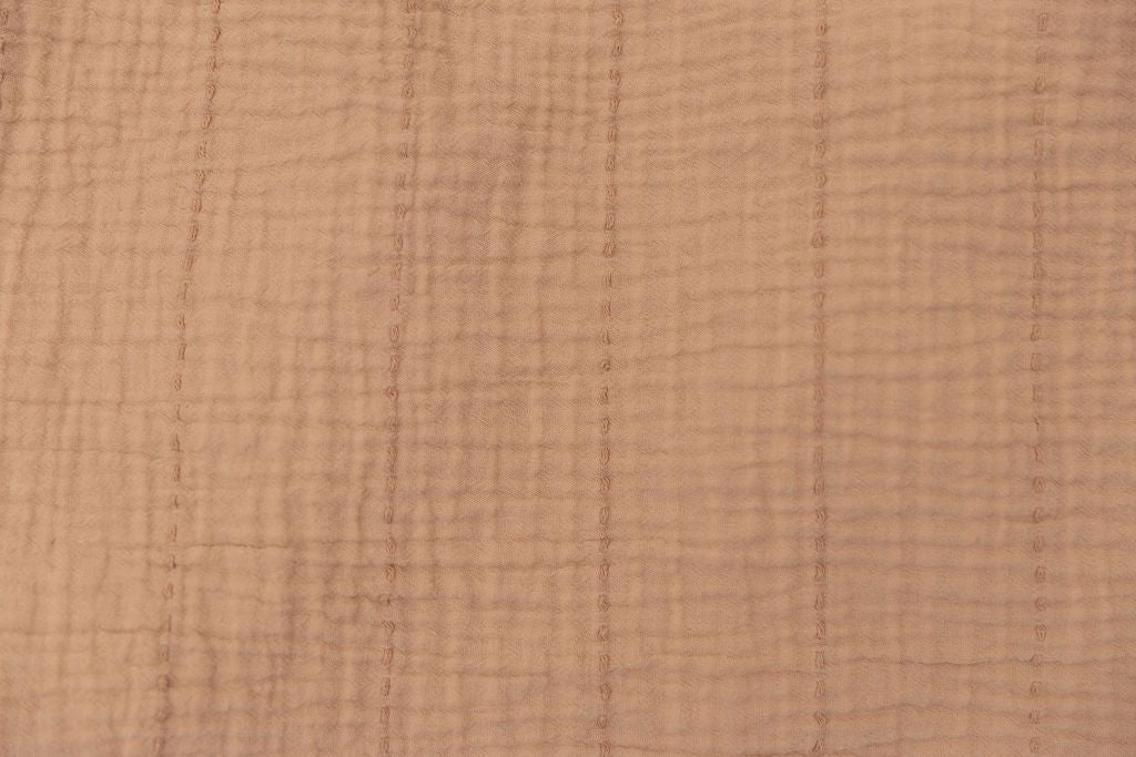 Close up on the terra cotta color of a seersucker throw blanket
