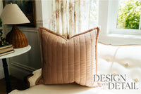 A terracotta quilted pillow on a cream antique coach. 