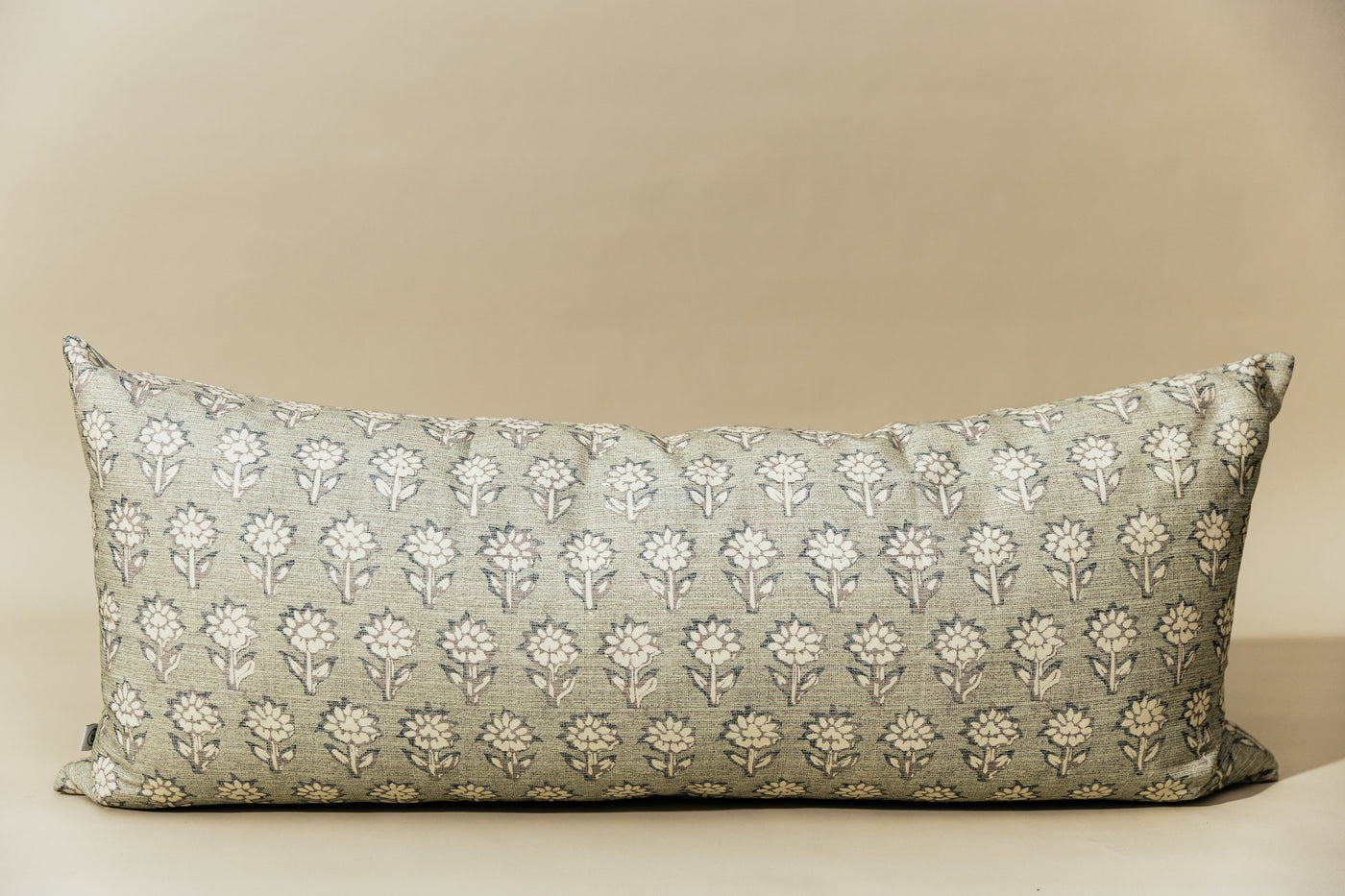 A sage green and blue floral pattern XL lumbar pillow arranged on a light green background.
