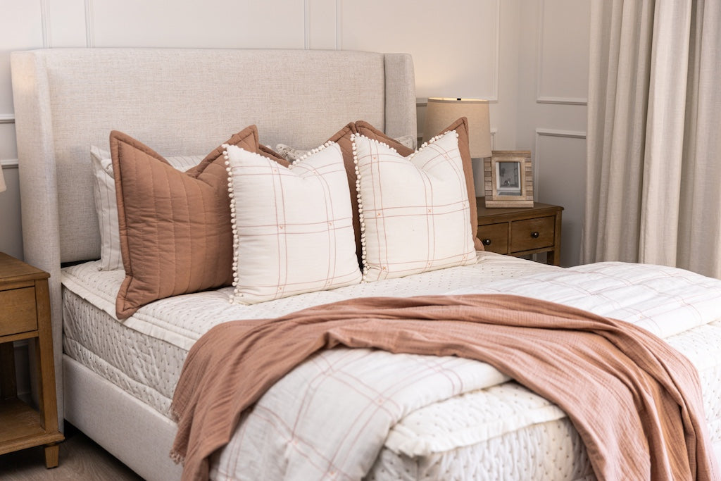 Cream stitch X zipper bedding with white and pink striped pillows and terracotta accessories.