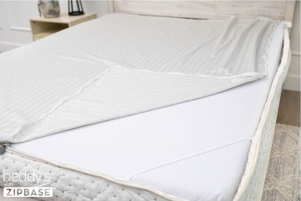 A ZipBase sheet partially unzipped and pulled back to show how it detaches from the rest of the base sheet wrapped around the sides of the mattress.