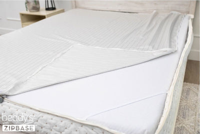 A ZipBase sheet partially unzipped and pulled back to show how it detaches from the rest of the base sheet wrapped around the sides of the mattress.
