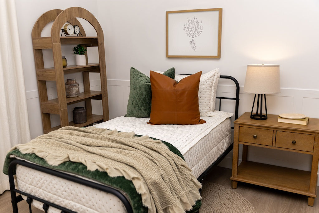 Twin bed with cream stitch X zipper bedding with tan and green accessories.