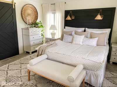 A bed made with cream embroidered zipper bedding and adorned with neutral pattern pillows and a throw blanket.