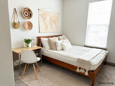 A bed made with cream embroidered zipper bedding and adorned with neutral pattern pillows and blanket.