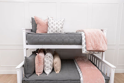 A bunk bed where both bunks are made with gray zipper bedding and an assortment of floral and pink bedding accessories