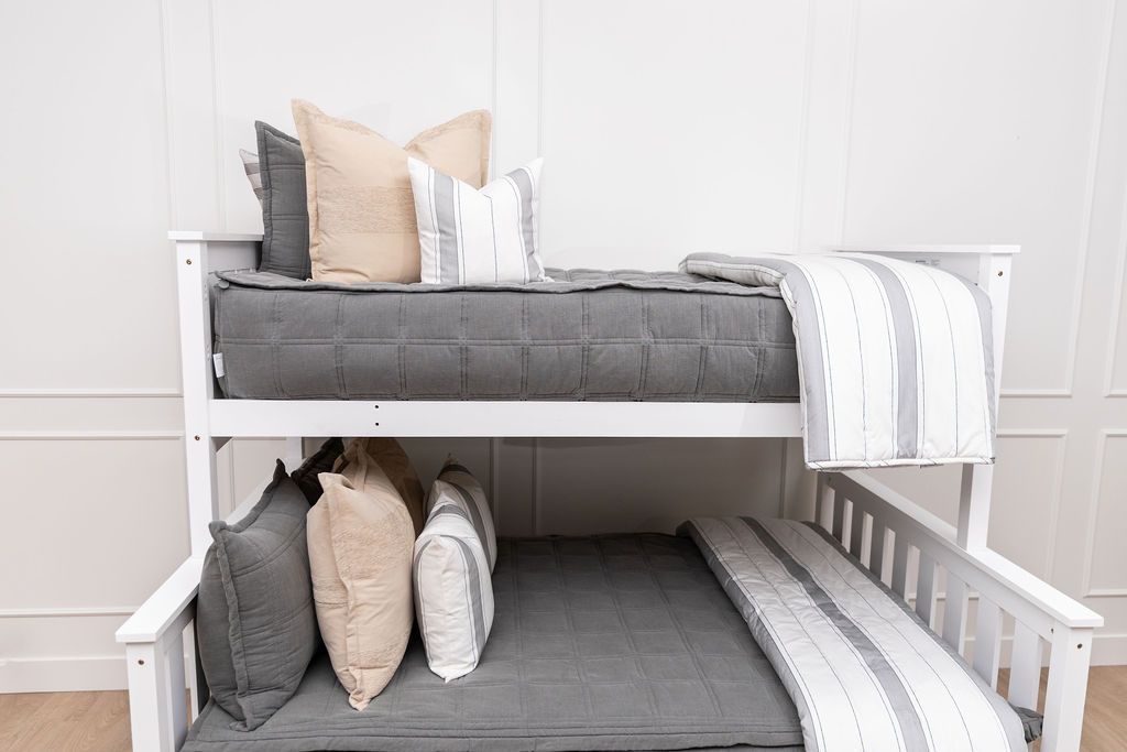 A bunk bed where both beds are made with gray zipper bedding with neutral bedding accessories