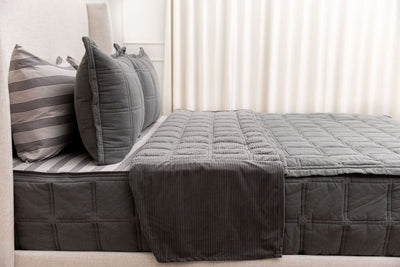 A bed made with gray zipper bedding with the top unzipped and pulled back to show the inside lining