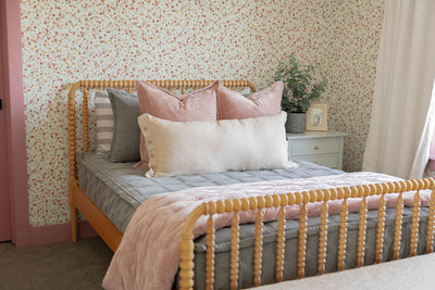 a girls bed made with gray zipper bedding and pink bedding accessories