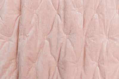 A close up view of a light pink velvet blanket. 