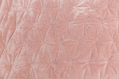 A close up view of a pink velvet blanket. 
