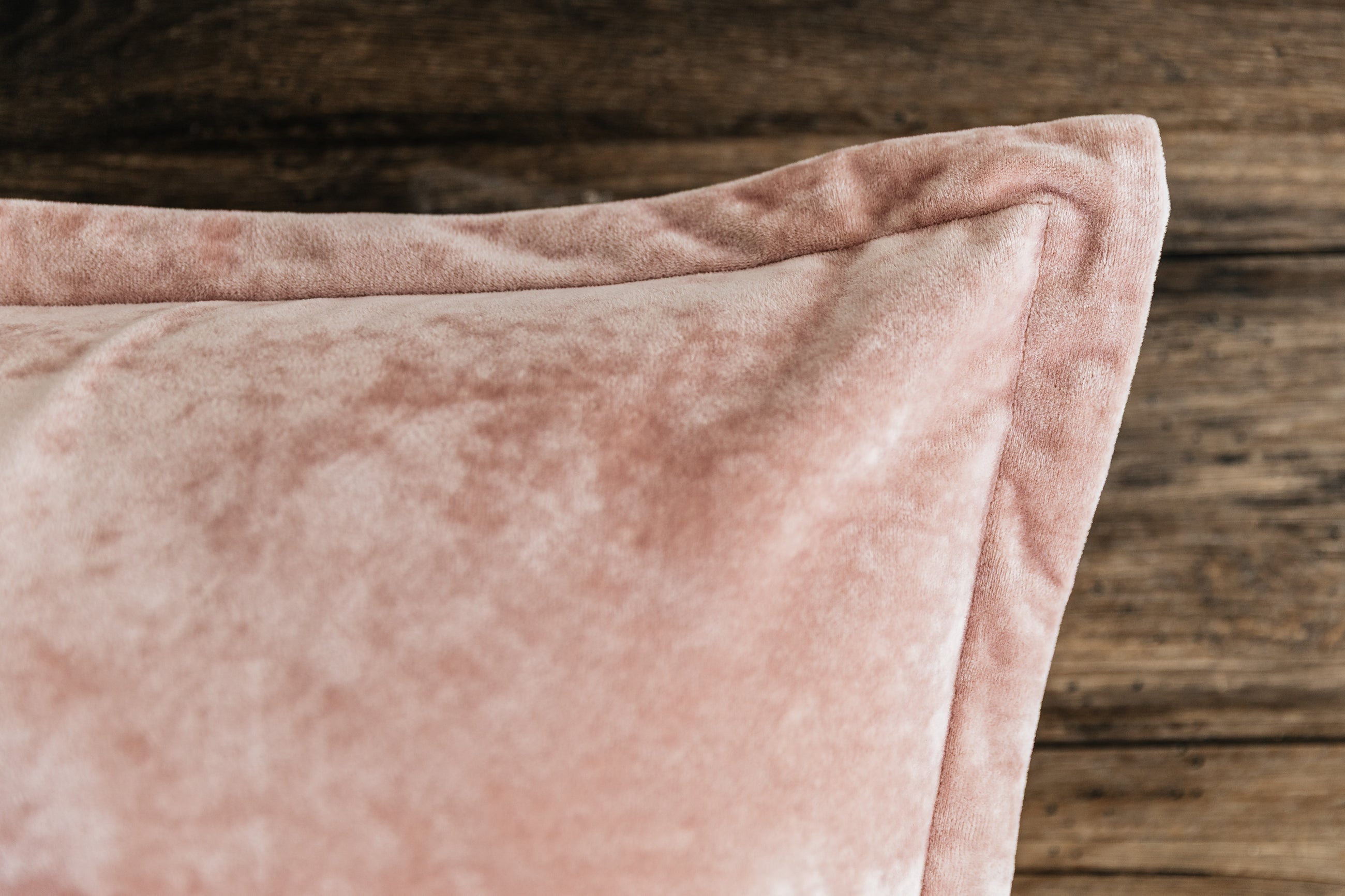 A close up corner view of a pink velvet euro pillow.