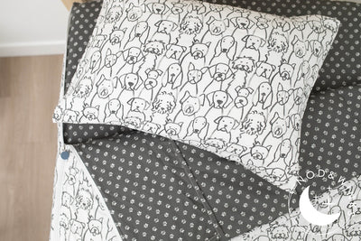 A twin bed made with charcoal and white pattern dogs kids zipper bedding, the top unzipped and slightly pulled back and a pillow on the bed.