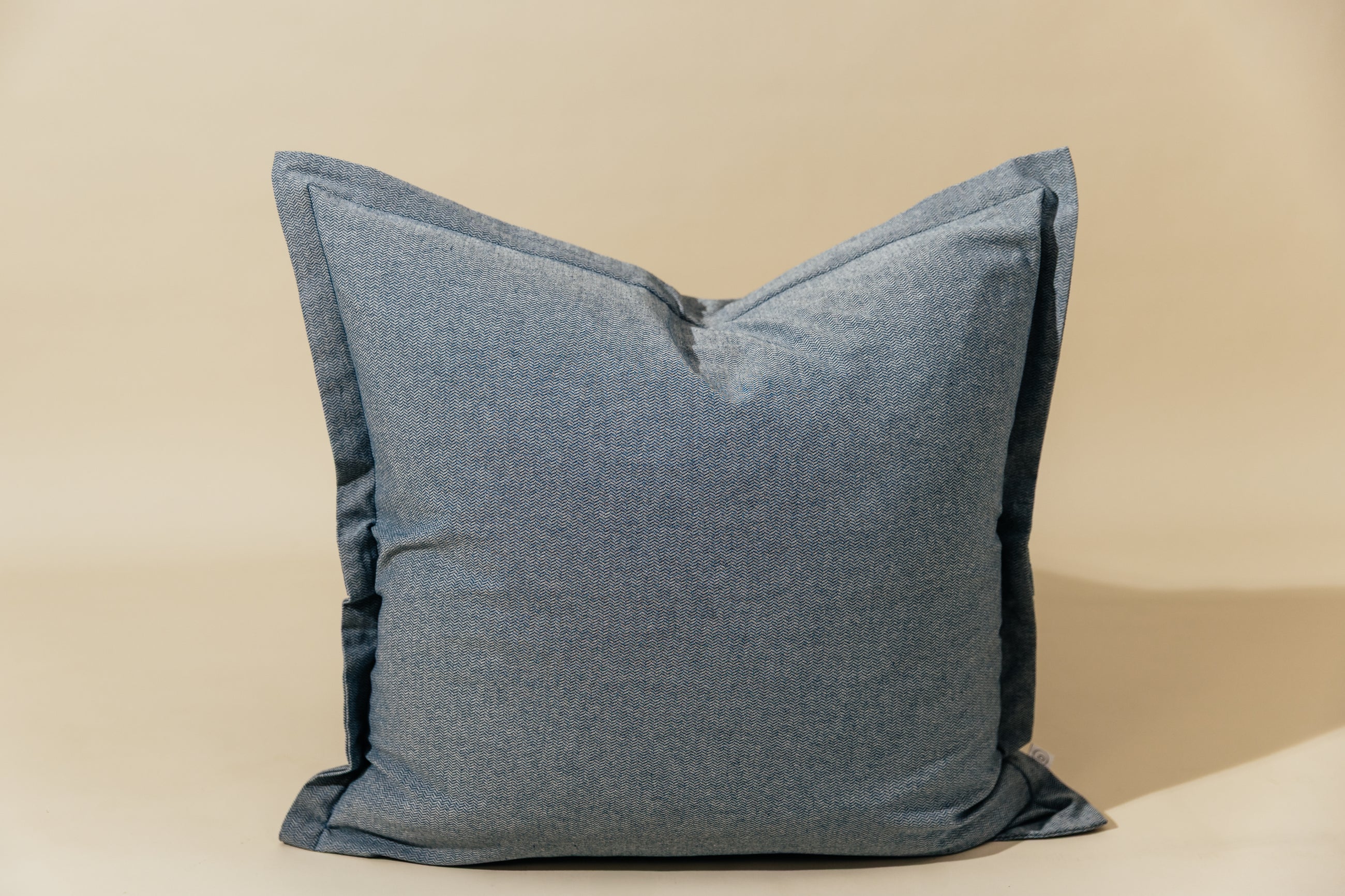 A blue two-toned herringbone euro pillow arranged on a cream background.