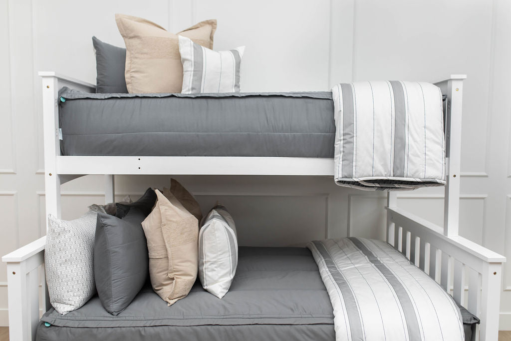 A standard bunk bed with both bunks made with gray zipper bedding and neutral and gray striped pillows and blankets.