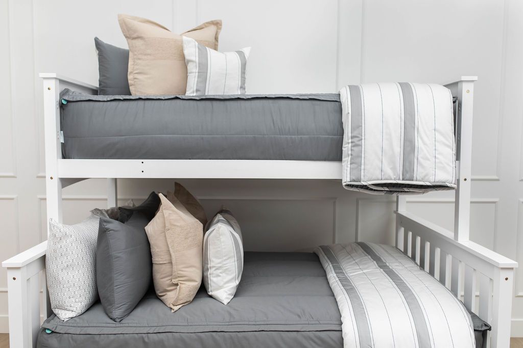 A standard bunk bed with both bunks made with gray zipper bedding and neutral and gray striped pillows and blankets.