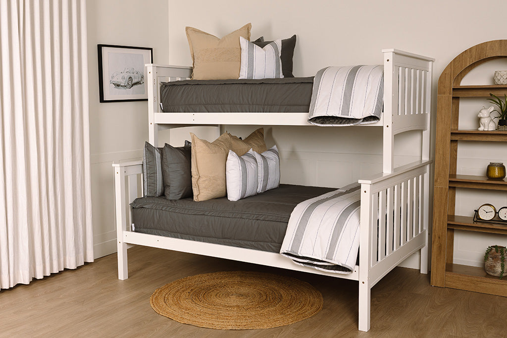 A bunk bed made with gray zipper bedding and an assortment of neutral and striped throw pillows and blanket.