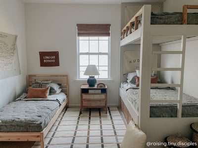 A standard bunk bed and another twin bed with all beds made with deep emerald green zipper bedding and neutral throw pillows.
