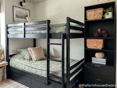 A standard bunk bed with both bunks made with deep emerald green zipper bedding and neutral throw pillows.