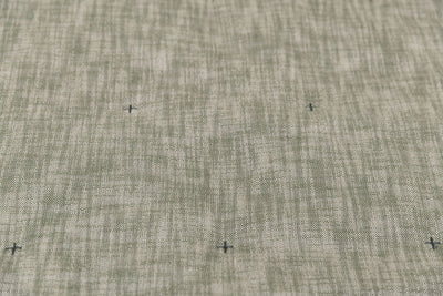 A close up view of a deep emerald green two-toned woven tweed exterior with embroidered cross-hatches of a zipper bedding.