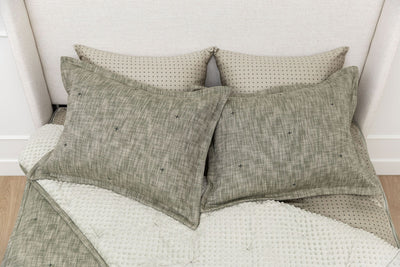 A bed made with deep emerald green zipper bedding with the comforter pulled back and pillows on top of the bed.