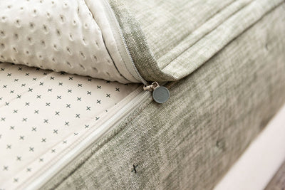 A close up view of a bed made with deep emerald green zipper bedding with the bed slightly unzipped to reveal the minky comforter and the khaki crosshatch patterned bottom cotton lining.