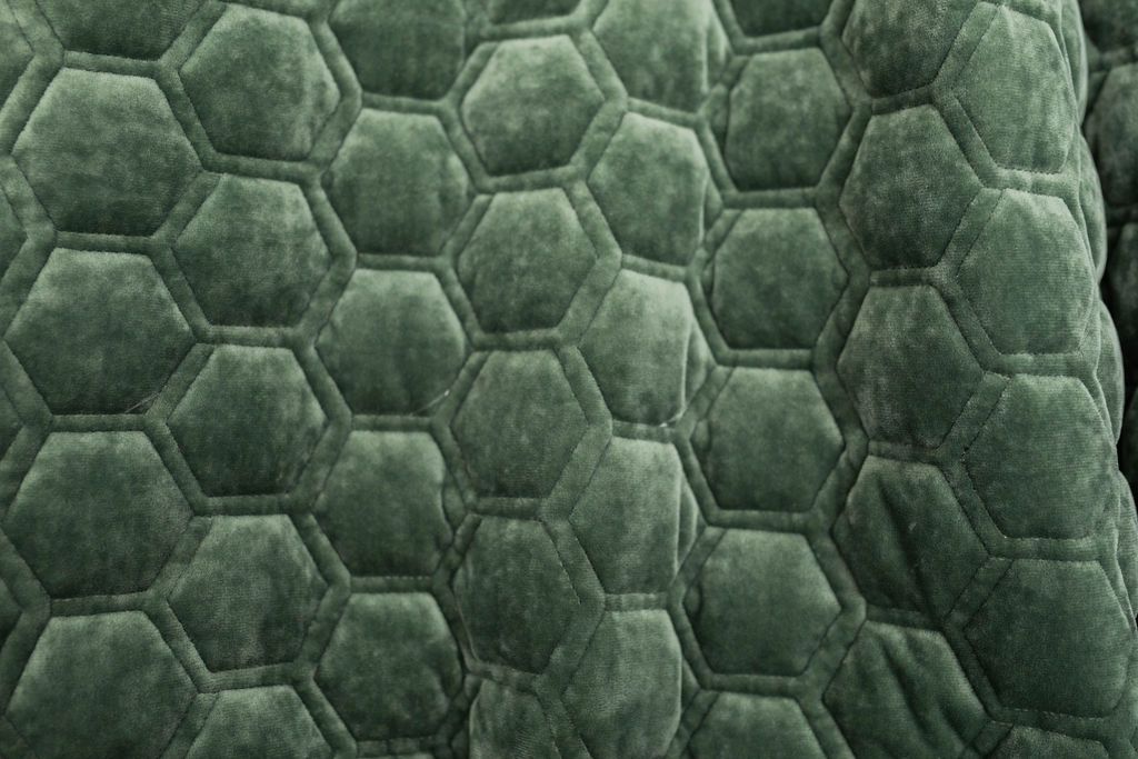 A close up of an emerald honeycomb pattern velvet blanket.