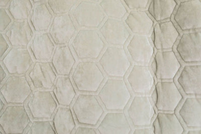 A close up of a buff gray honeycomb velvet blanket.