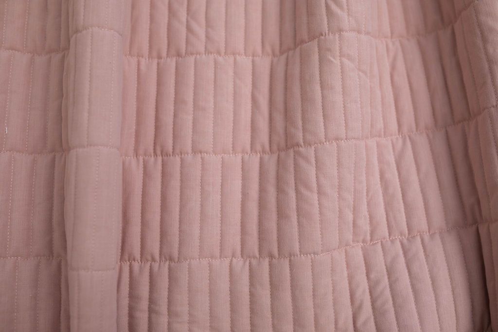 A close up of a pink piano key quilted blanket.