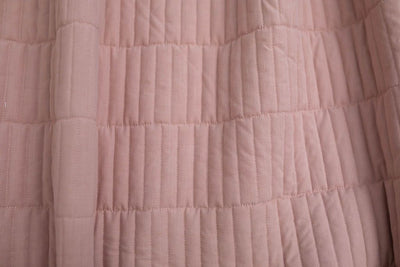 A close up of a pink piano key quilted blanket.